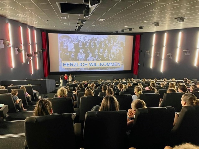 Schülerinnen sitzen im Kino-Saal. Auf der Leinwand läuft der Film