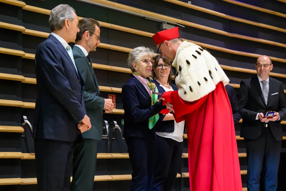 Ein Mann in einer roten Robe mit Hermelinkragen überreicht  mehreren Männern und Frauen eine Medaille