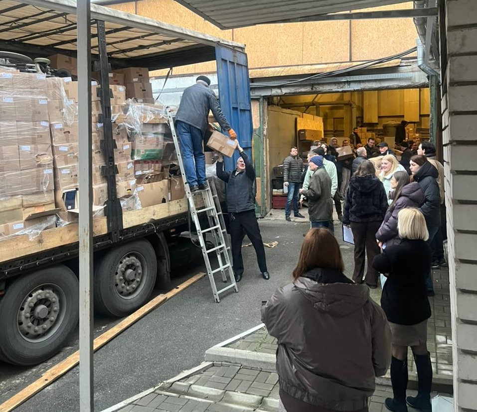 Menschen stehen neben einem mit Kartons beladenen Lastwagen und laden diesen aus