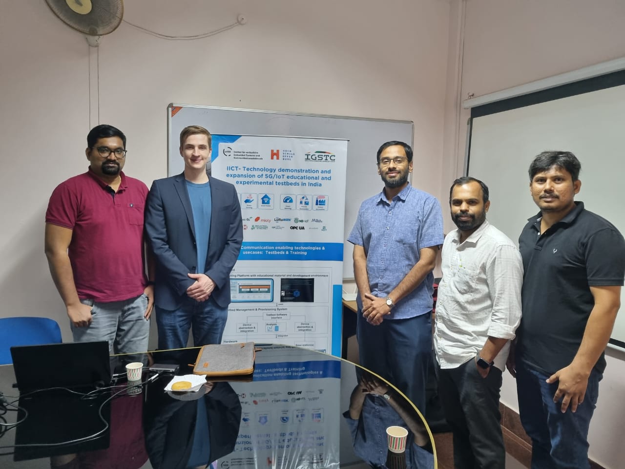 fünf Männer stehen links und rechts von einem Plakat