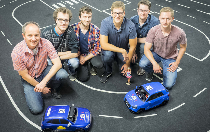 Gruppenfoto mit zwei Modellfahrzeugen auf dem Parcours