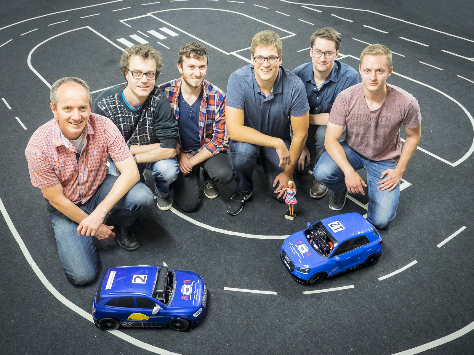 Gruppenfoto mit zwei Modellfahrzeugen auf dem Parcours